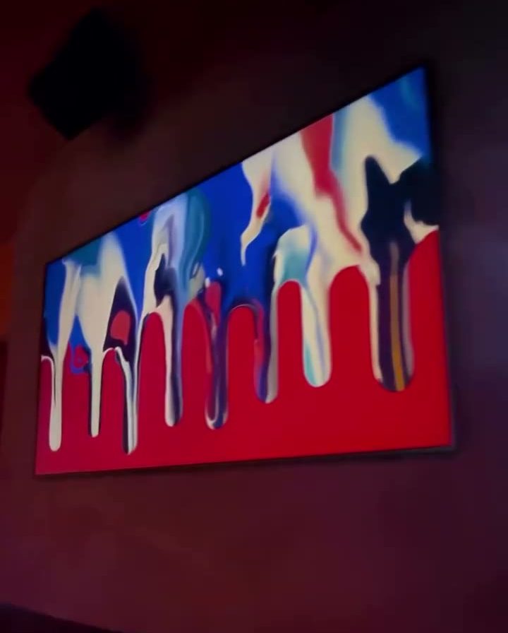 Rotating local artwork glowing on one of the venue art screens